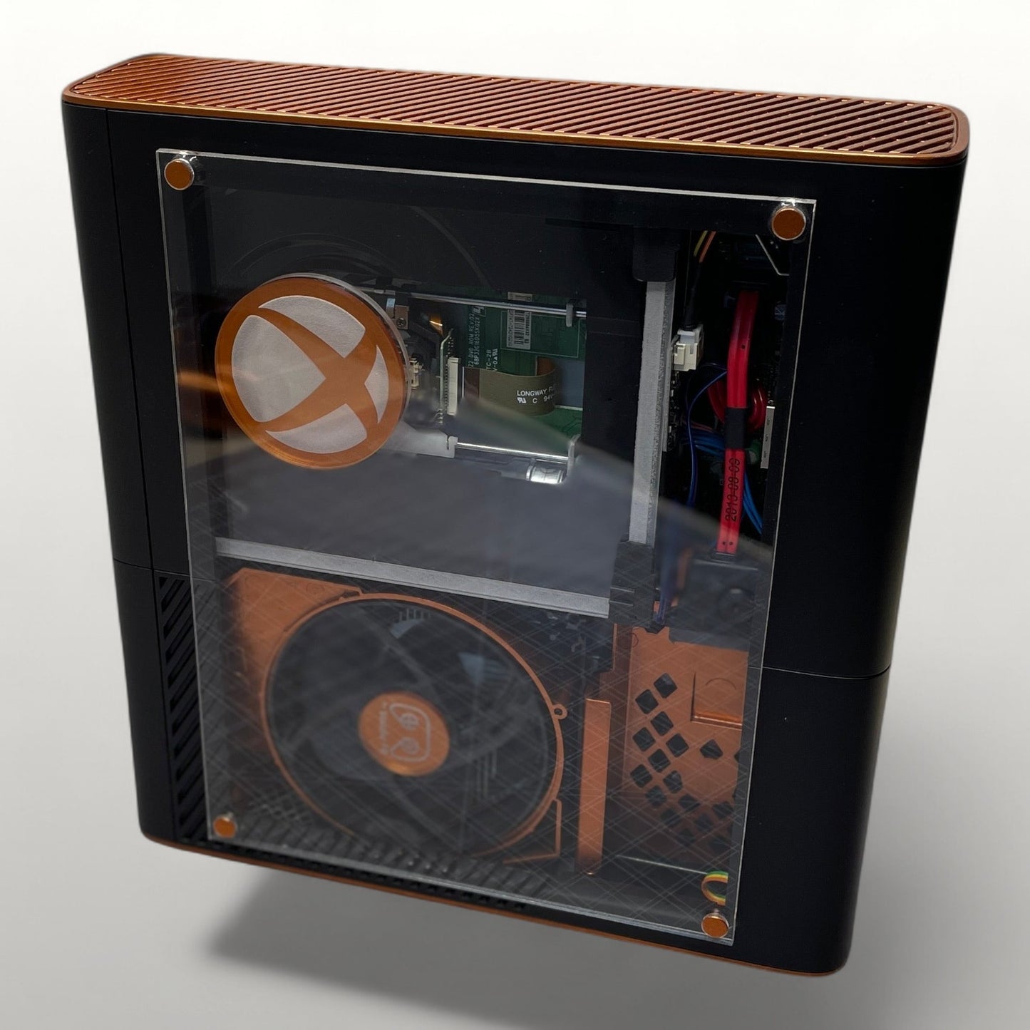 StudioFR custom black and copper Xbox 360E console with clear side panel showing internal components and RGB lighting.
