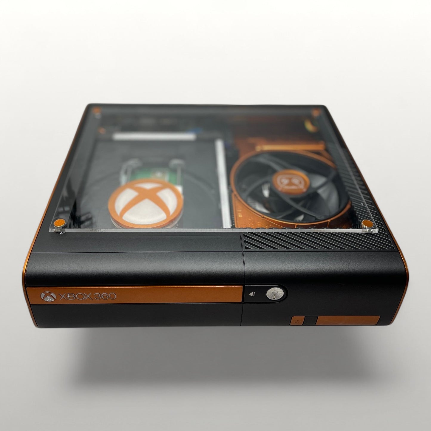StudioFR custom black and copper Xbox 360E console with clear top window showing internal components and RGB lighting.