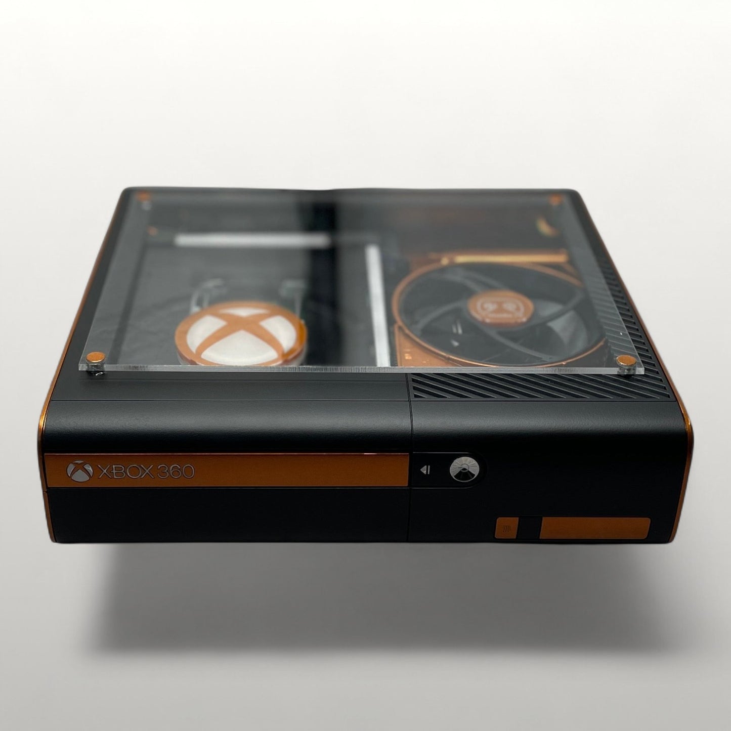 StudioFR custom black and copper Xbox 360E console with clear top window showing internal components and RGB lighting.
