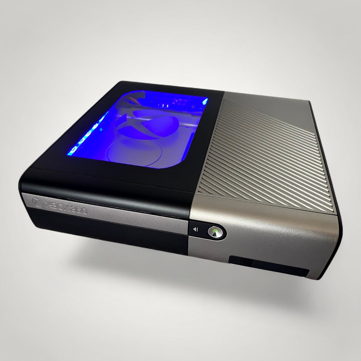 StudioFR customized black and grey Xbox 360E console with RGB lighting visible through a window mod.