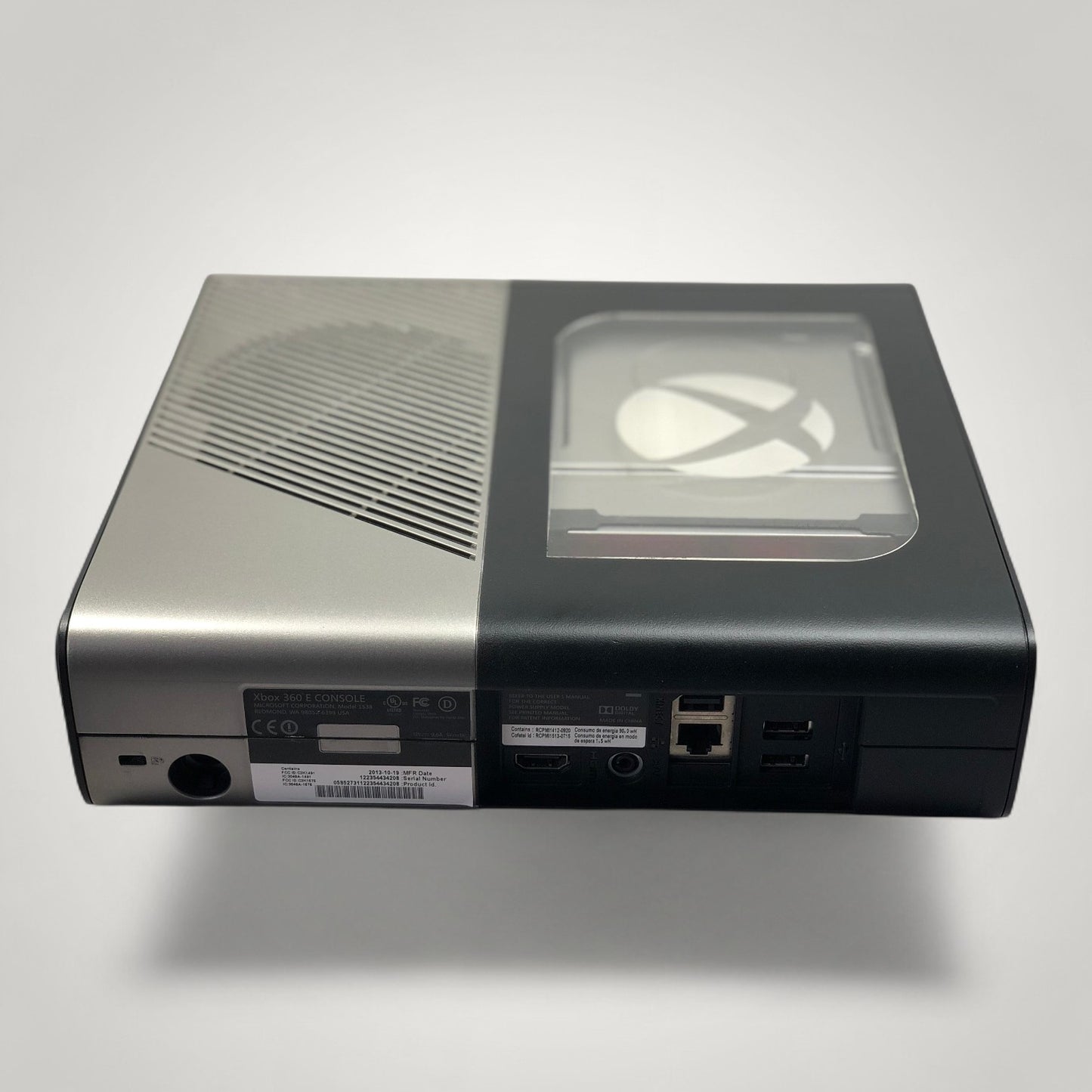 StudioFR customized black and grey Xbox 360E console with a clear window mod revealing the Xbox logo.