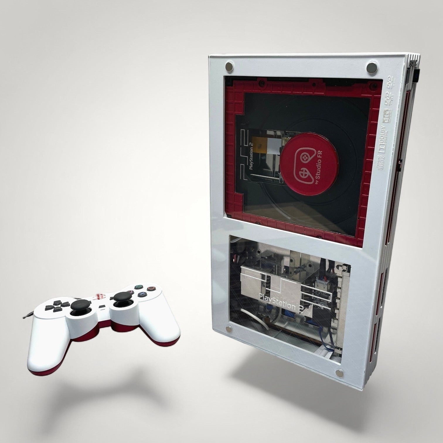 StudioFR customized red and white PlayStation 2 Fat console with clear panels and a matching controller.
