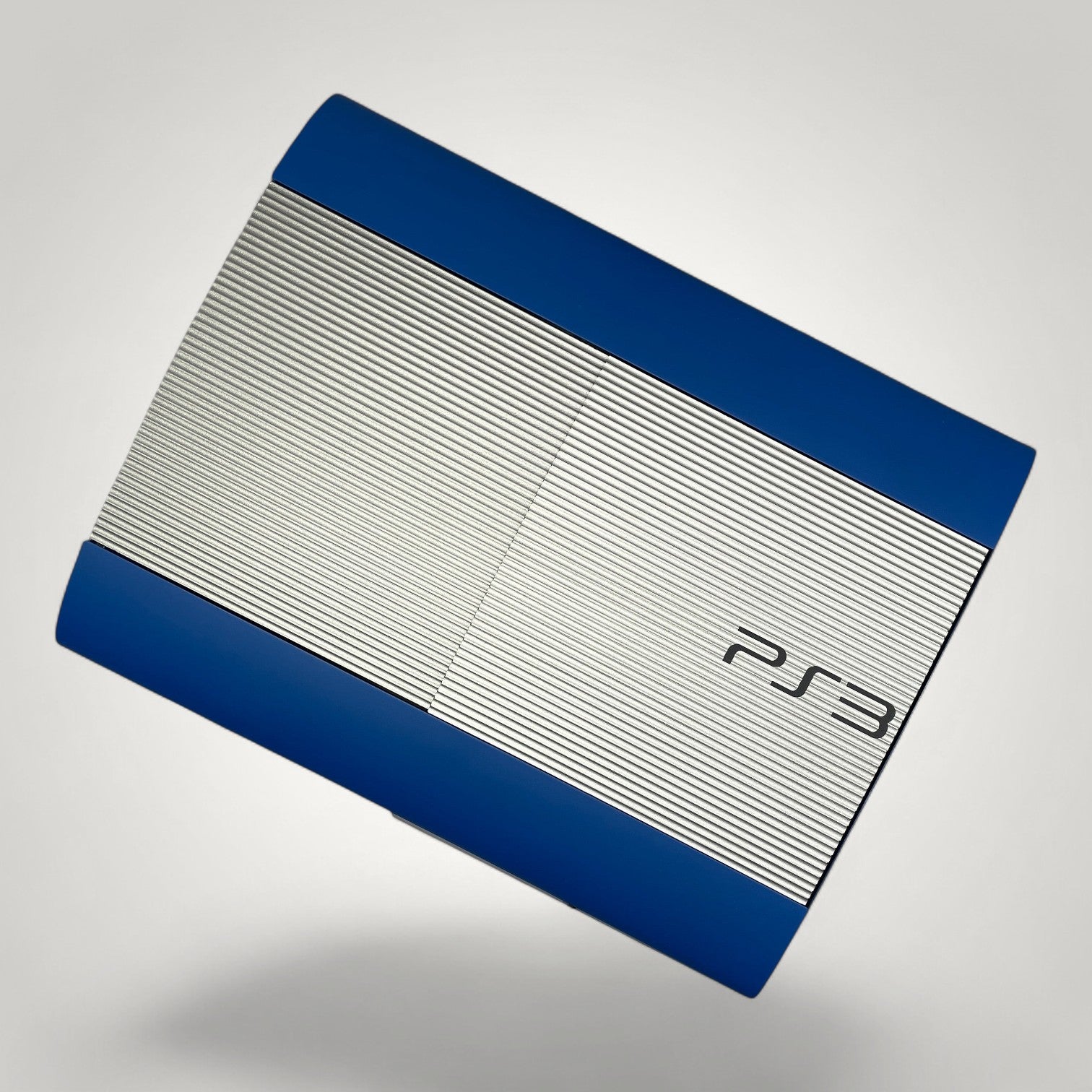 StudioFR customized PS3 Super Slim console in brushed steel and vibrant blue with PS3 logo.