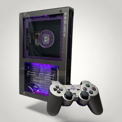 StudioFR custom purple and grey PlayStation 2 Fat console with RGB lighting and matching controller.