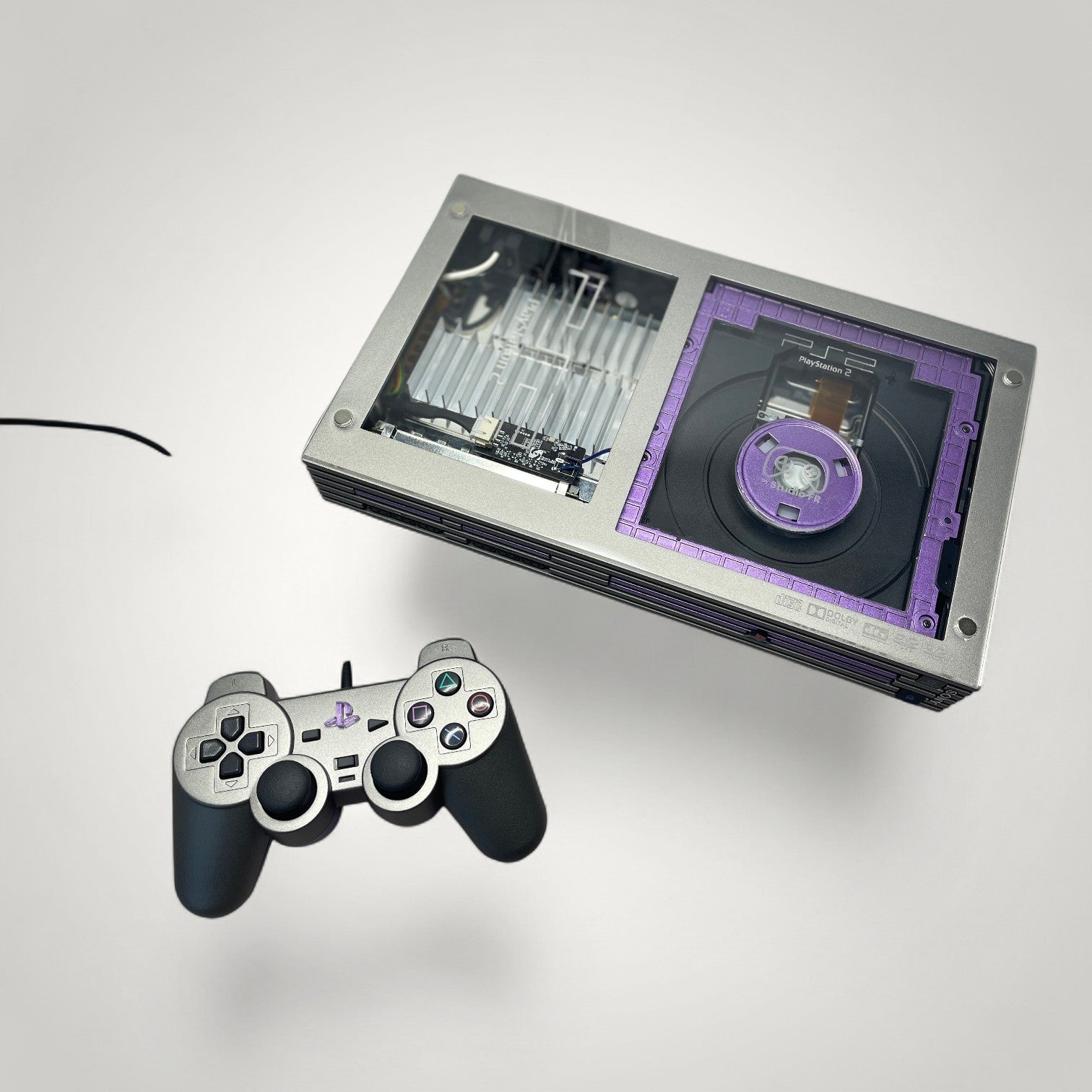 StudioFR custom purple and grey PS2 Fat console with clear top, RGB lighting, and matching controller.