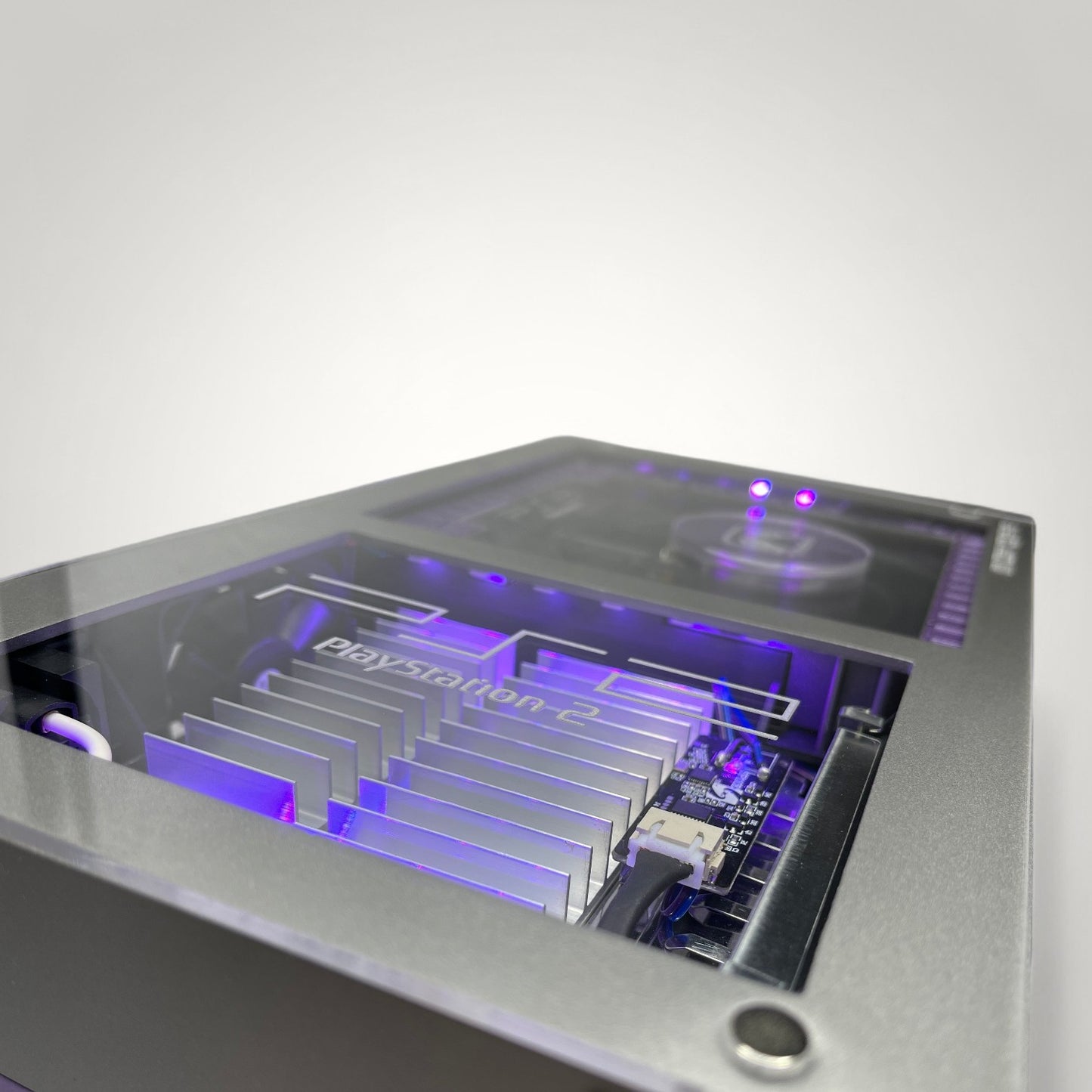 StudioFR customized purple and grey PlayStation 2 Fat console with internal RGB lighting and clear top.