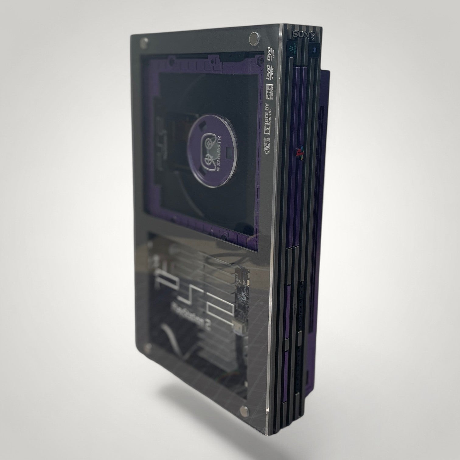 StudioFR custom purple and grey PlayStation 2 Fat console with clear case showing internal components and RGB lighting.