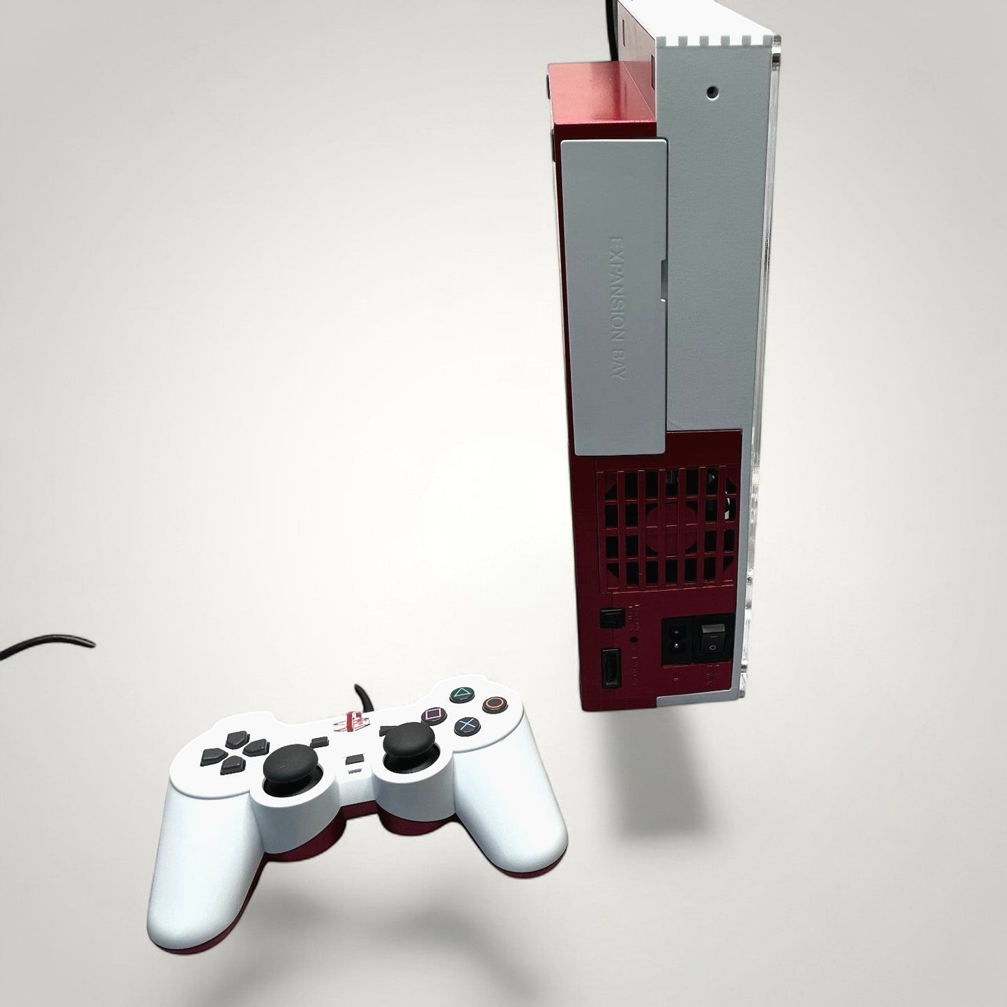 StudioFR customized red and white PlayStation 2 Fat console with matching controller. Features RGB lighting and custom engraved logos.