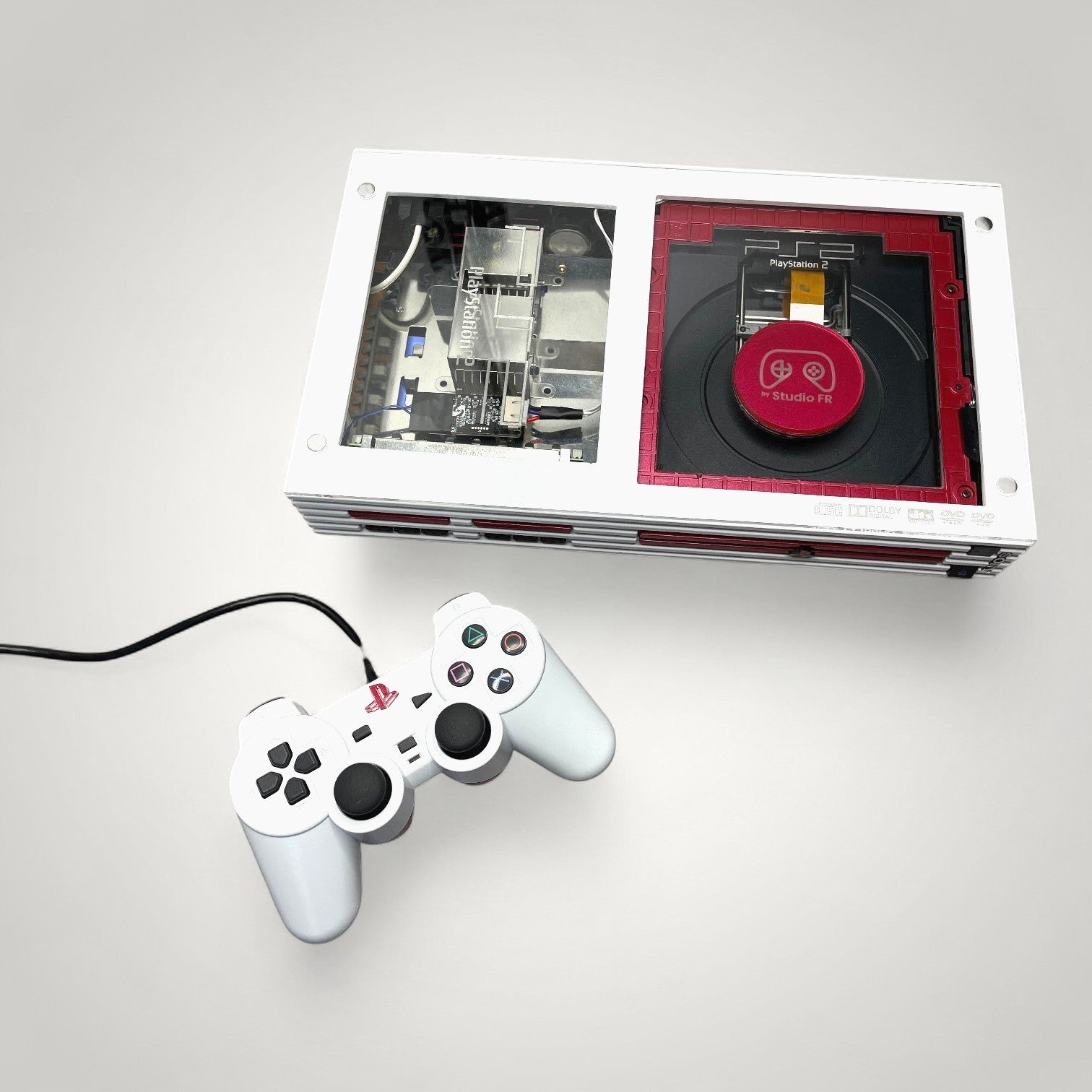 StudioFR customized red and white PlayStation 2 Fat console with clear top and matching controller.