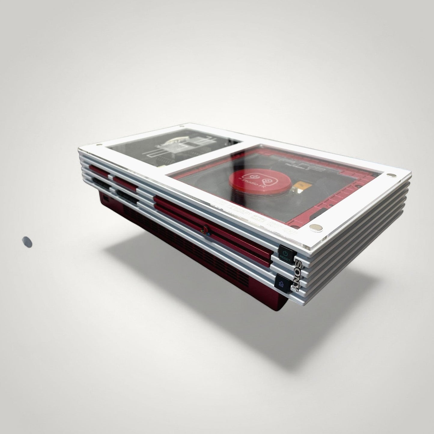 StudioFR customized red and white PlayStation 2 Fat console with clear top showing internal components and RGB lighting.