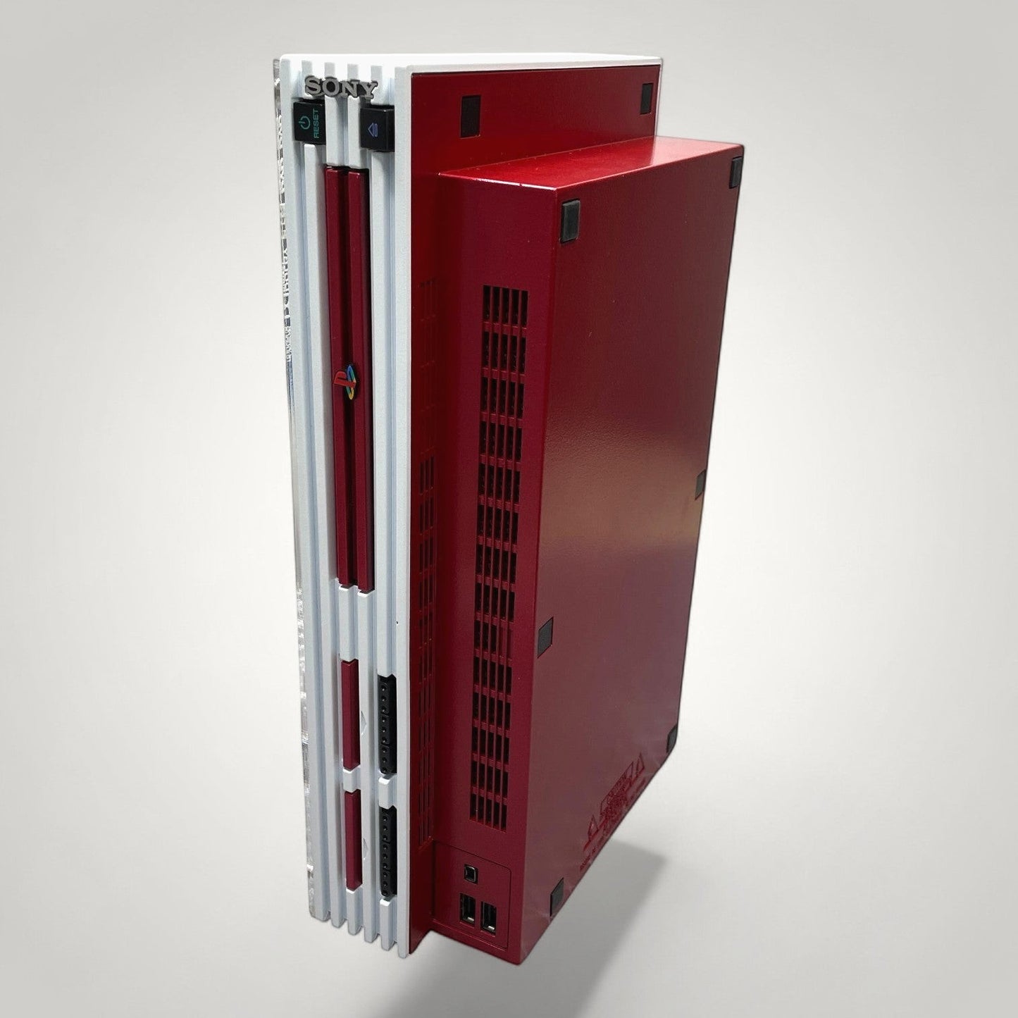 StudioFR customized red and white PlayStation 2 Fat console with silver accents and engraved logos.