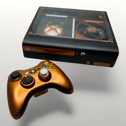 StudioFR custom black and copper Xbox 360E console with matching controller. Features a clear top window with RGB lighting.
