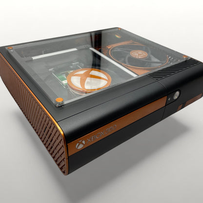 StudioFR customized black and copper Xbox 360E console with clear top window showing internal components and RGB lighting.