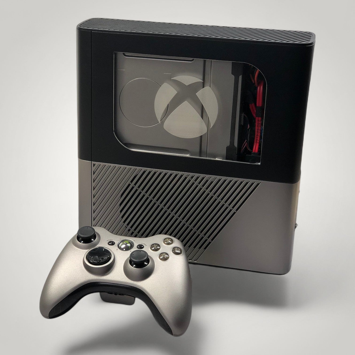 StudioFR custom black and grey Xbox 360E console with window mod and matching controller. RGB lighting visible.